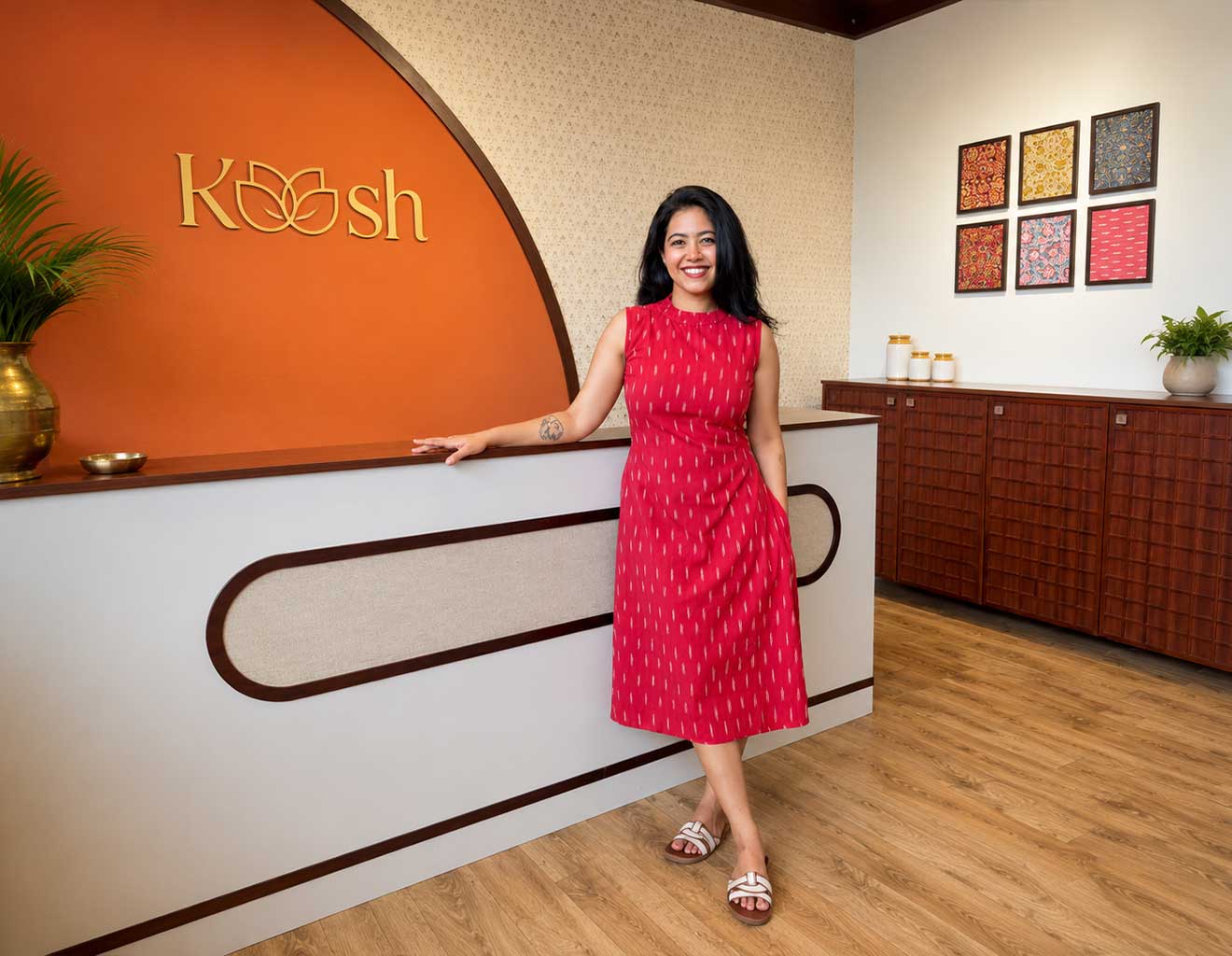 Woman in a red dress standing in front of a counter with a 'Kosh' logo.