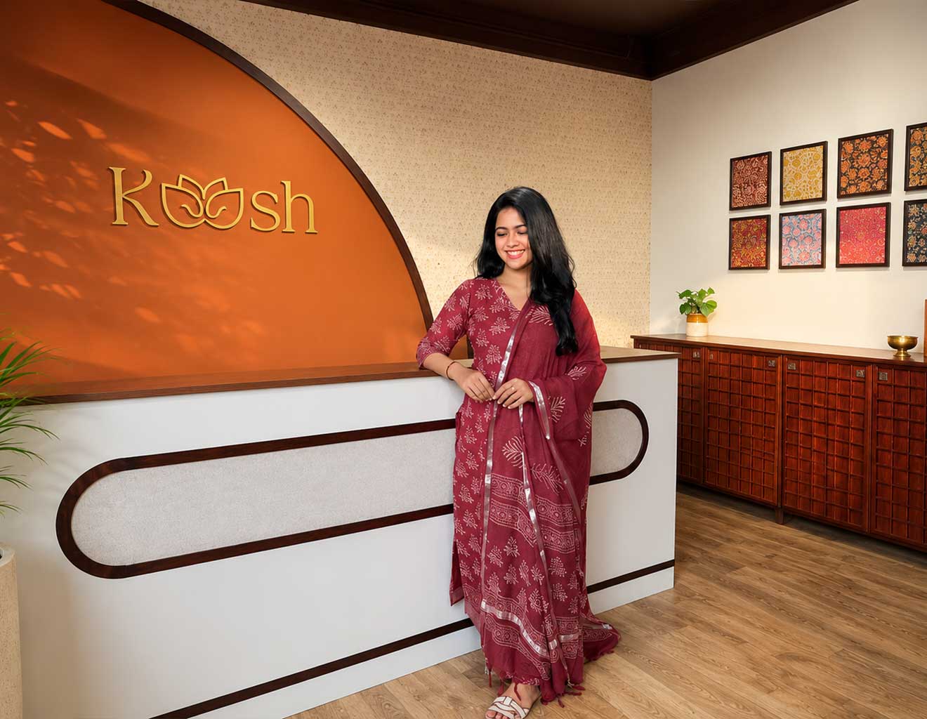 Woman in a red patterned dress standing in front of a 'Koosh' branded counter.
